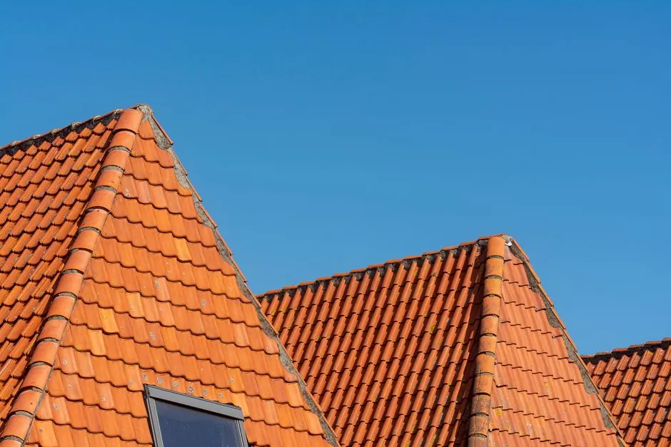 Close-up of red tiled roofs under a clear blue sky, showcasing architectural design.